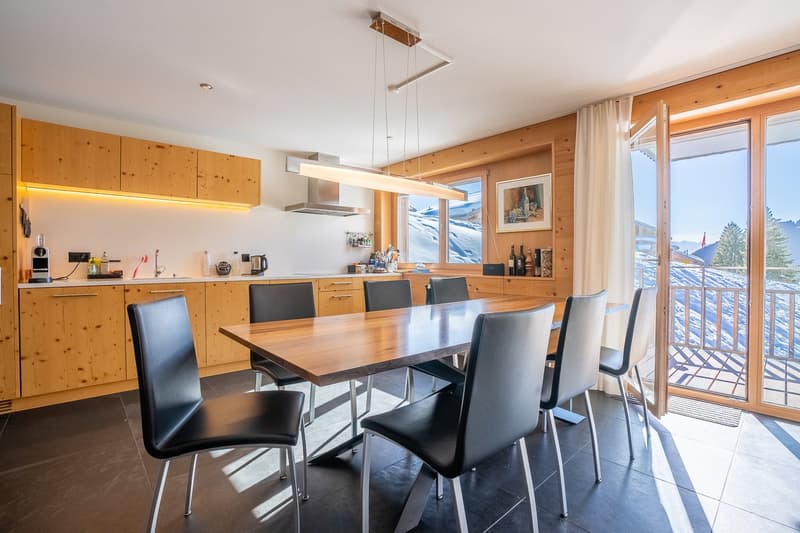 wooden dining table, black chairs, wooden cabinets, kitchen area, balcony, sliding glass door, view of snowy mountains