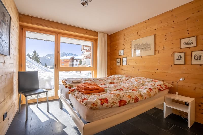 wooden walls, double bed, chair, bedside table, lamp, window, picture frames