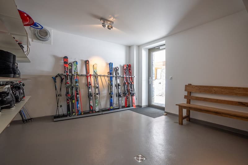 Storage room with skis, ski poles, helmets, and boots