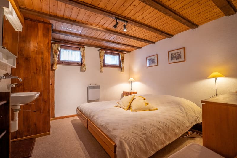 bedroom with bed, wooden walls, wooden ceiling, sink, radiator, lamps, windows, pillows