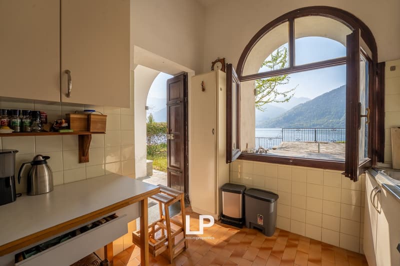 kitchen with a view of the lake, wooden counter, tiled floor, open door, wooden stools, trash bins, clock, open window