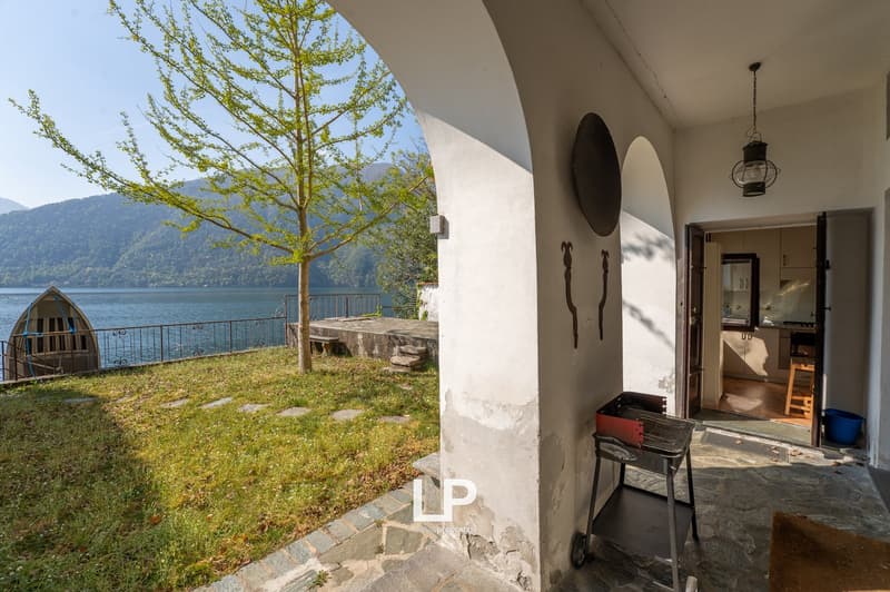 House with a view of the lake, tree, grass, and mountains in the background