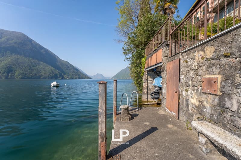 Lakefront property with a dock, stone wall, and a boat in the water.