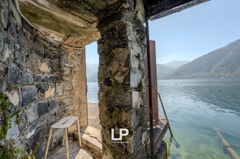 Stone wall, wooden stool, open door, lake view, mountains in the background