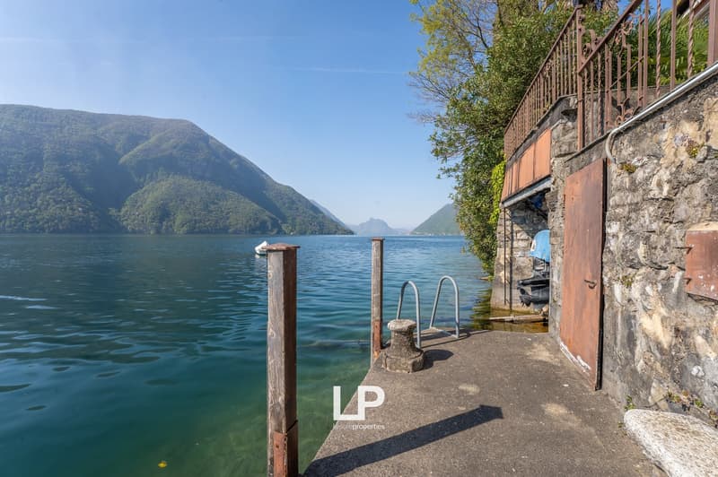 Stone wall, wooden pier, railing, water, mountains, boat