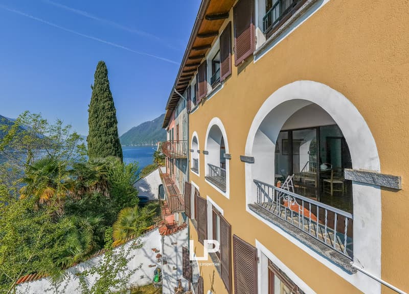 Building with balconies, yellow and white walls, arched windows, view of the lake
