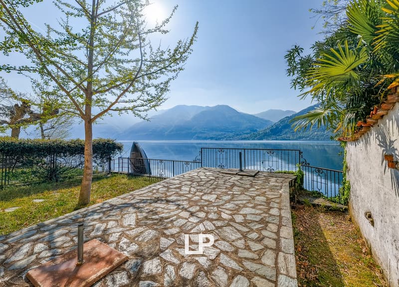 Stone pathway, lake view, metal fence, greenery, mountains in the background