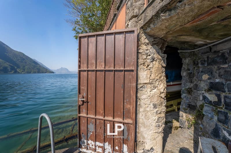 Stone wall, brown metal gate, water body, mountains in the background