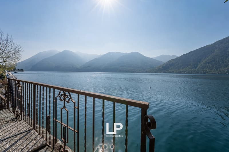 Balcony with railings overlooking a lake with mountains in the background