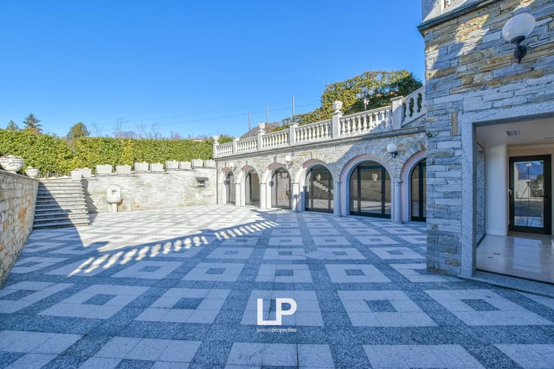 Stone exterior with balcony, stone pathway, hedges, stairs