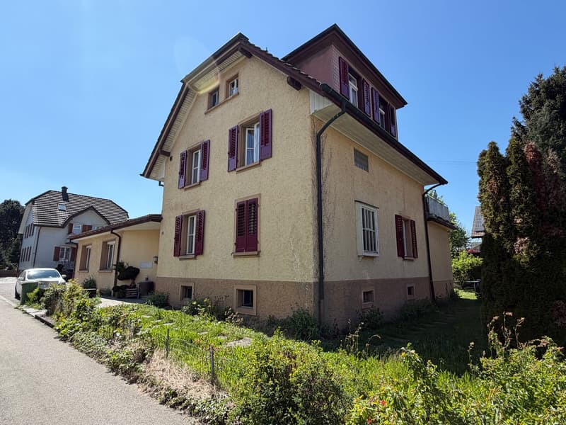3 story house, beige and brown exterior, red shutters, small garden, car parked in front