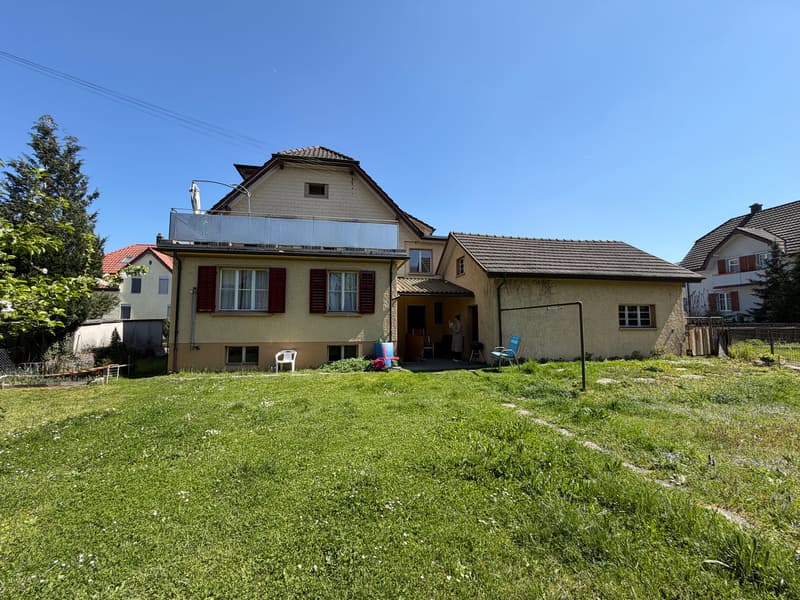 2 story house, brown roof, red shutters, balcony, large yard, solar panels