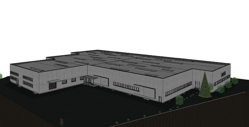 A gray warehouse with a flat roof and multiple windows, a covered entrance on the left side, and a concrete surface.