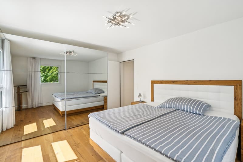 white walls, large mirror, wood floor, 2 single beds, nightstand with lamp