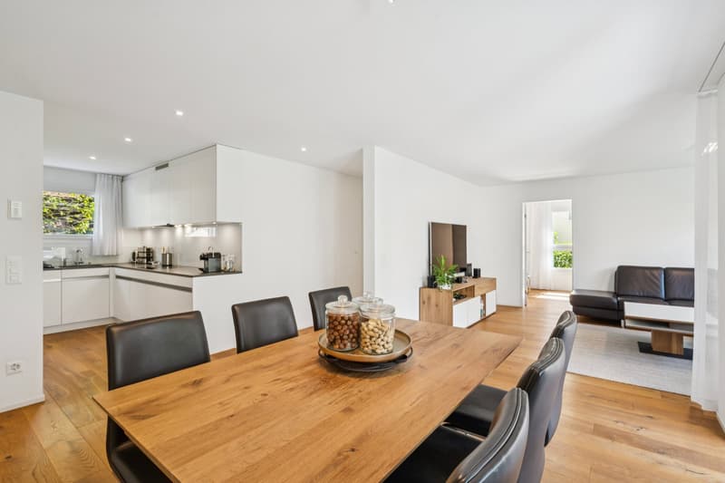 Modern dining room, wooden floor, wooden table, six black chairs, open kitchen, sofa, rug, TV