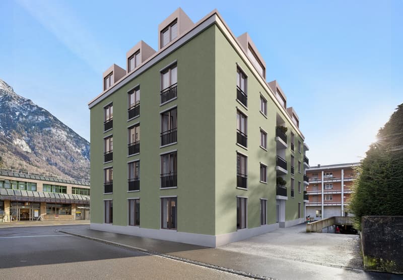 Green apartment building, multiple balconies, many windows, located in front of a mountain