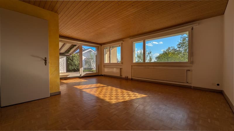 Unfurnished Room. Empty room with wooden flooring, large windows, and a slanted wooden ceiling. Natural light streams in, creating a bright and airy atmosphere.