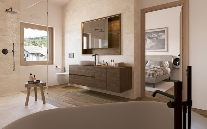 Modern bathroom with beige tiles, wooden cabinets, large mirror, bathtub, and open shower. Windows with a view of trees and mountains. Adjacent to a bedroom.
