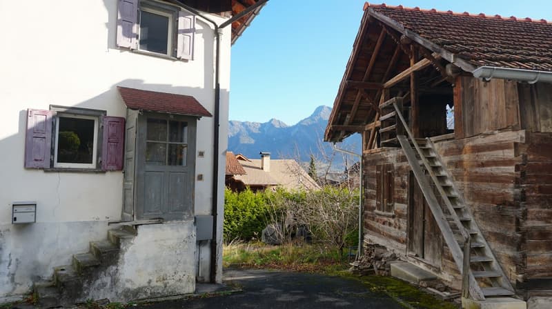 two old houses, mountains in the background, stairs leading to the entrance of the left house