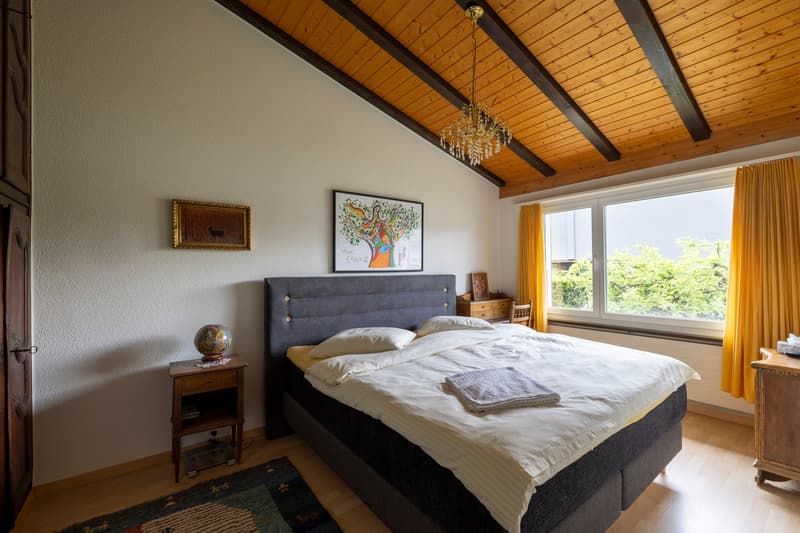 Bedroom with wooden ceiling, bed, nightstands, rug, picture frames, chandelier, window with curtains