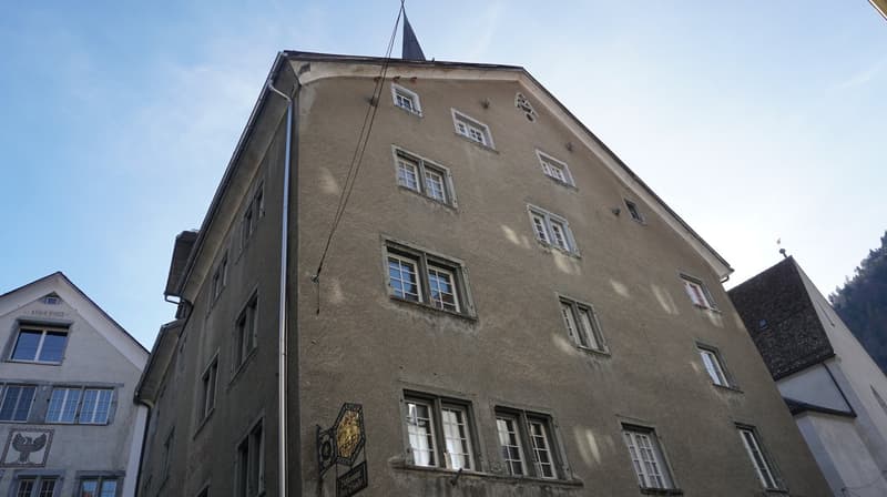 Multi-story residential building with many windows, a steeple, and a metal chimney