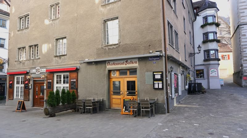 A building with a restaurant on the ground floor, outdoor seating, and a sign that reads 'Restaurant Falken'.