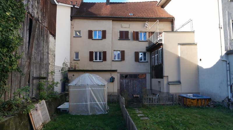 3 story house, brown roof, beige walls, wooden door, balcony, small greenhouse, small pool