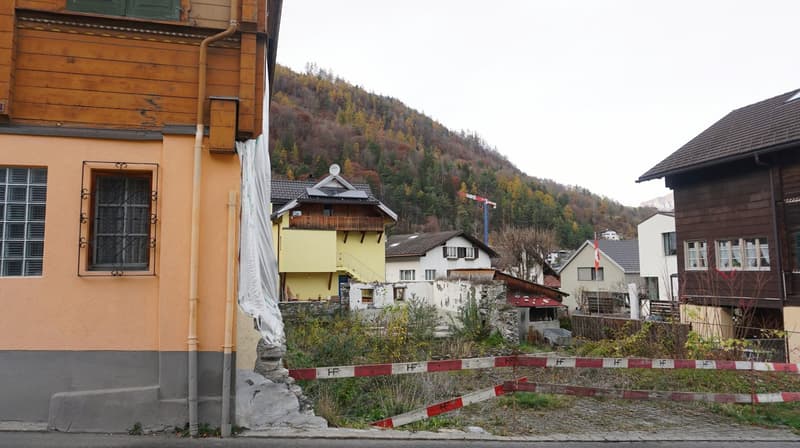 Wooden houses, yellow and brown, with a mountain in the background, a construction site, and a crane