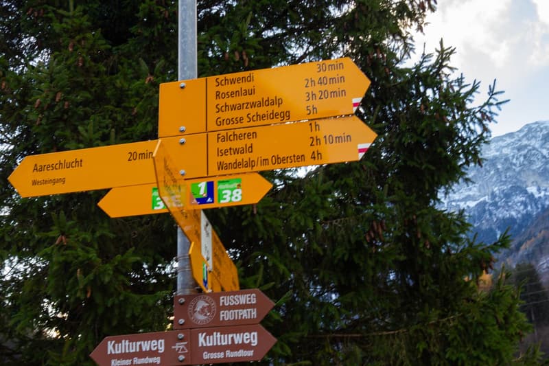 A signpost with multiple yellow signs indicating directions and distances to various locations.