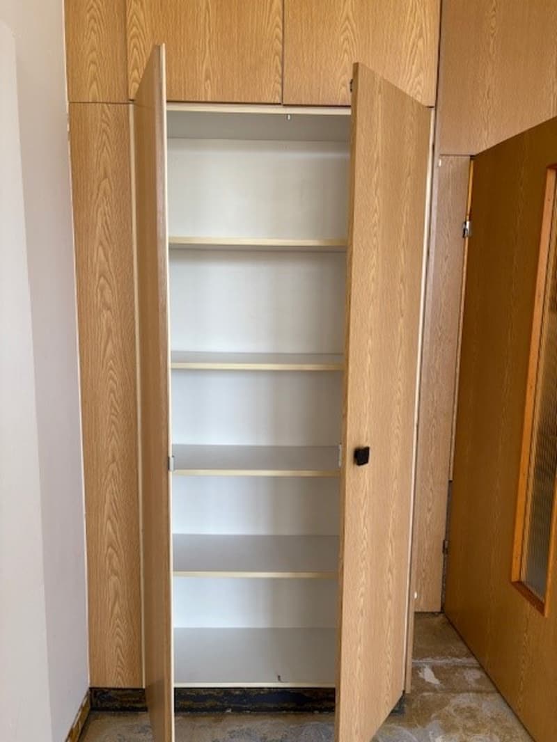 The image shows a built-in closet with wooden paneled doors. The closet has multiple shelves visible inside, providing storage space.
