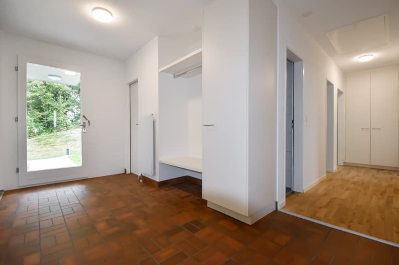 empty room, white walls, brown tile floor, glass door, bench, white shelves, radiator