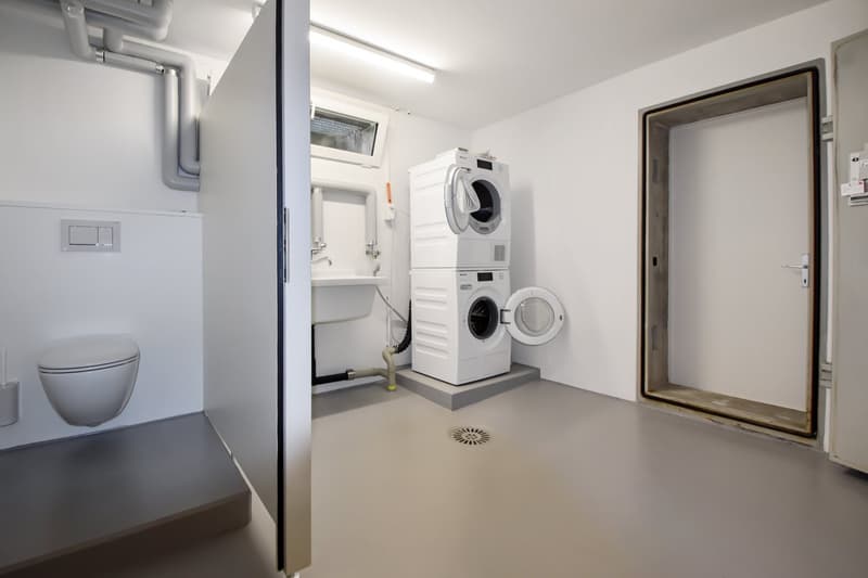 Laundry area, white walls, tiled floor, toilet, sink, washing machine and dryer