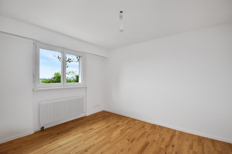 Empty room with wooden floor, white walls, white radiator, double window