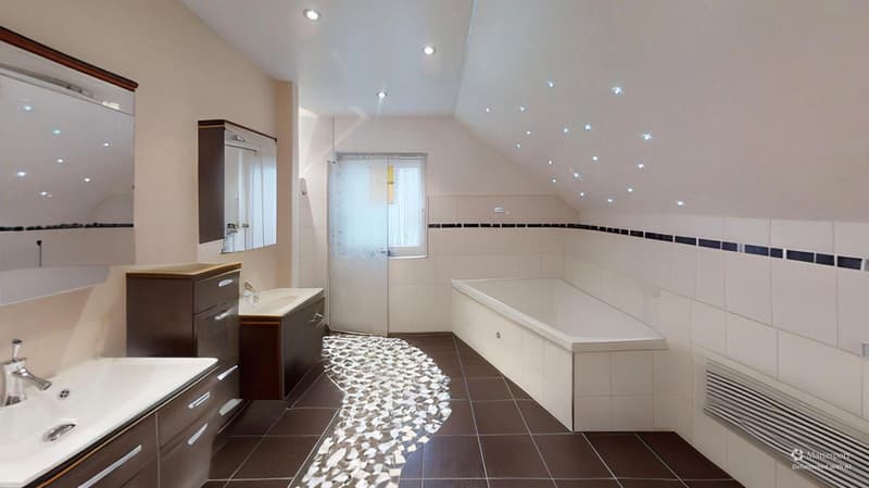 white bathroom, brown tiles, bathtub, modern sinks, vanity with mirror, white walls