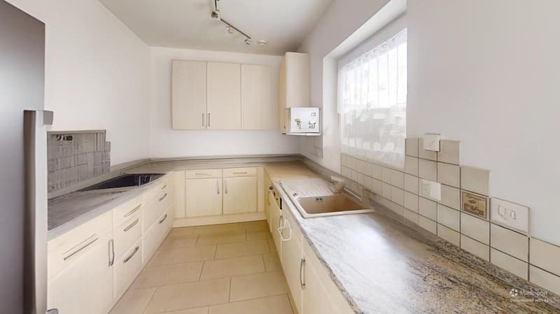 Modern kitchen with granite countertops, stainless steel sink, light grey tiled flooring, wooden cabinets, two sinks, ceiling track lighting