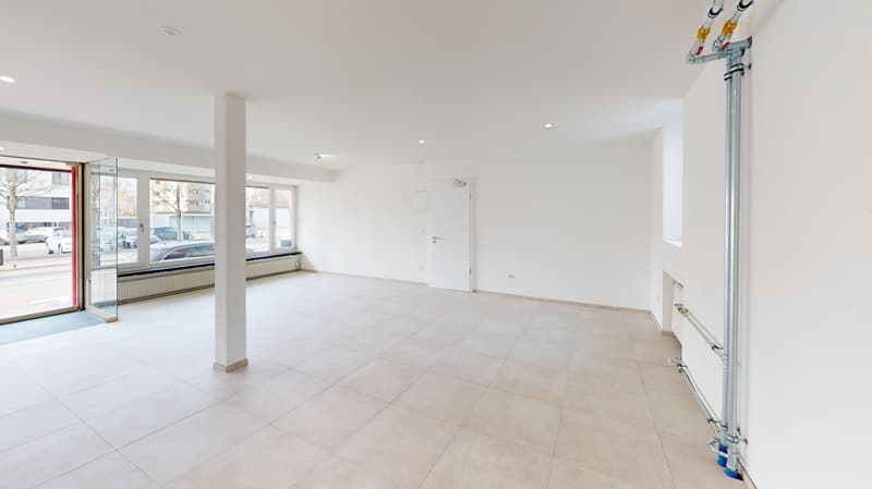 Empty room, white tile flooring, glass doors, large windows, white walls, pipe in wall