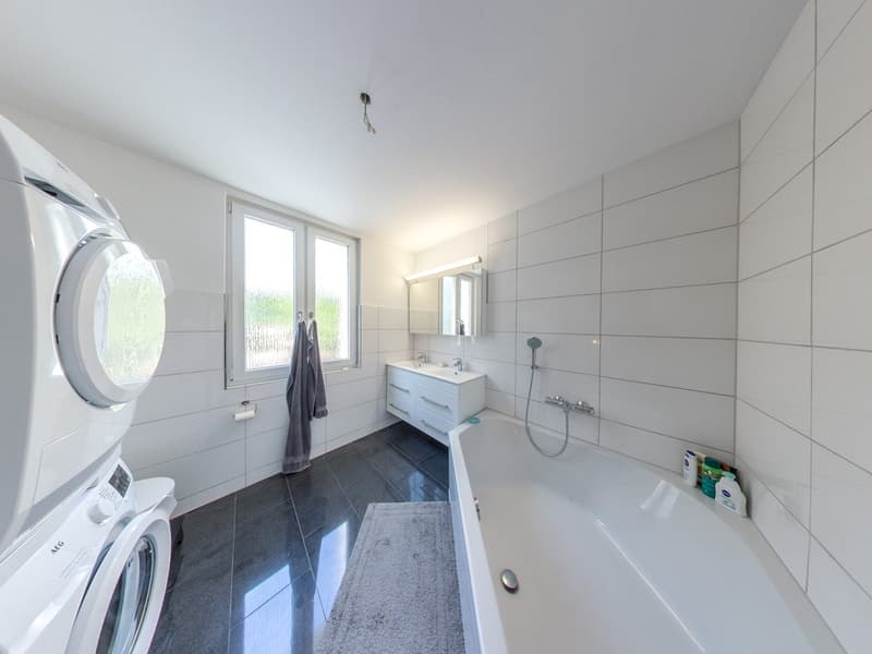 white tiles, white bathtub, white sink, white washing machine, white toilet, grey rug, grey towel
