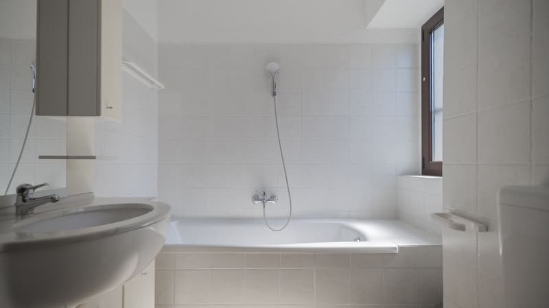 White tiles, white bathtub, showerhead, silver faucet, white sink, glass window, tiled floor