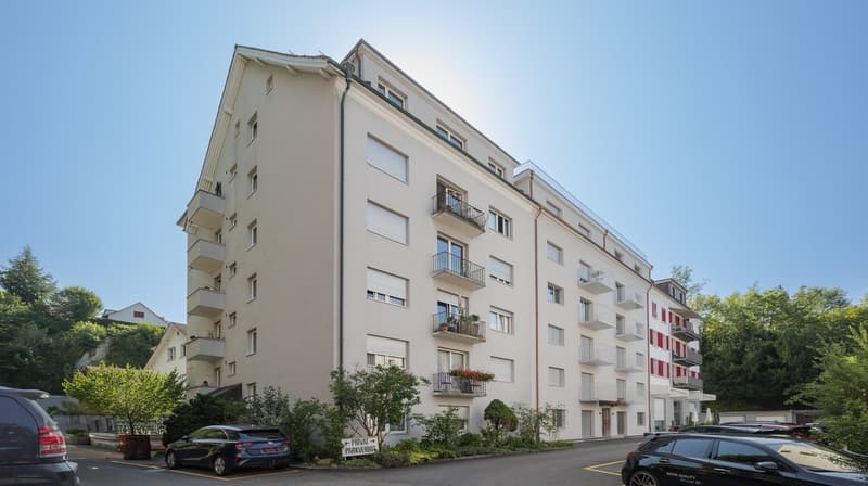 5 story building, balconies, parking lot, greenery