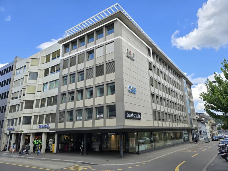commercial building, multistory, glass facade, shops on ground floor, car parked in front