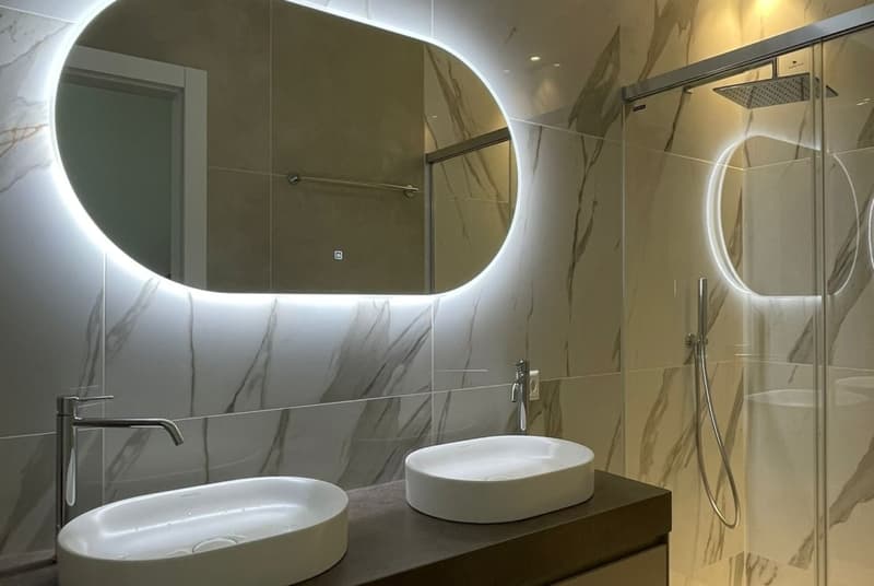 modern bathroom with double sink, shower, large mirror with lighted edges, marbled wall design