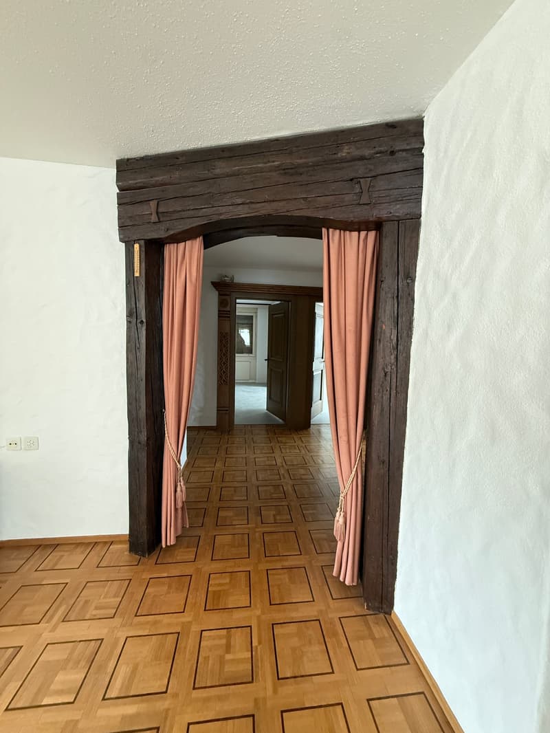wooden beams, wooden floor, white walls, pink curtains, open door