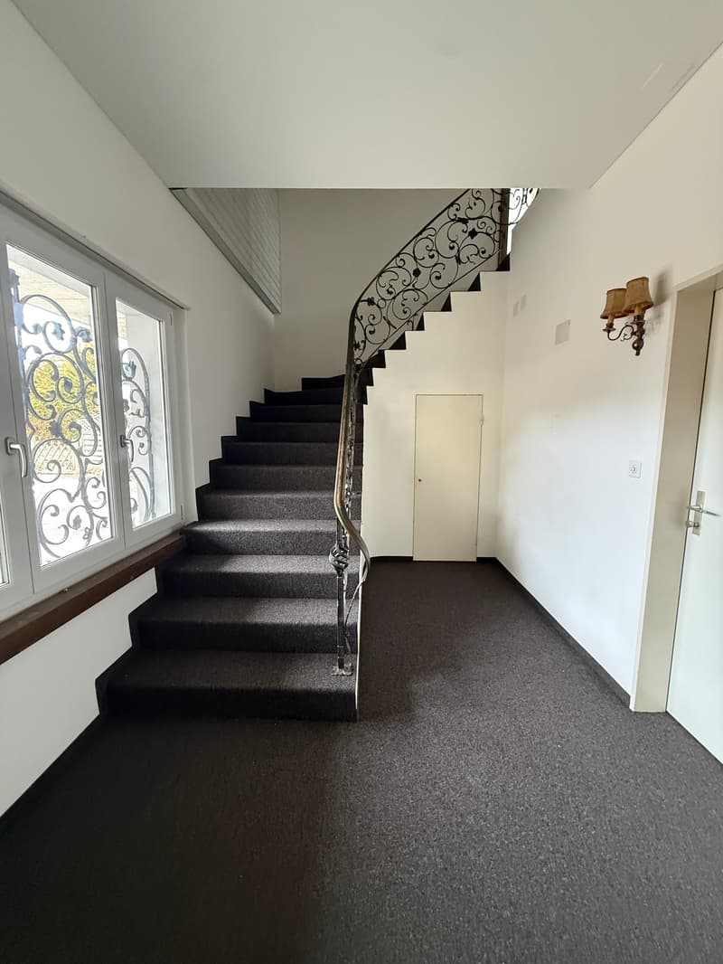 staircase with carpeted steps, white walls, white ceiling, white door, window with decorative glass, wall lamp