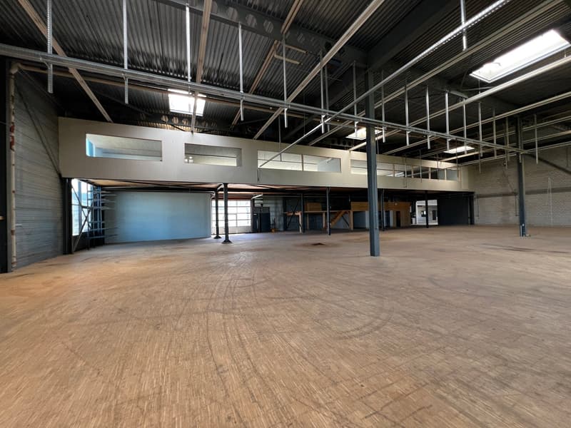 large open space, metal beams, wooden floor, windows, metal doors