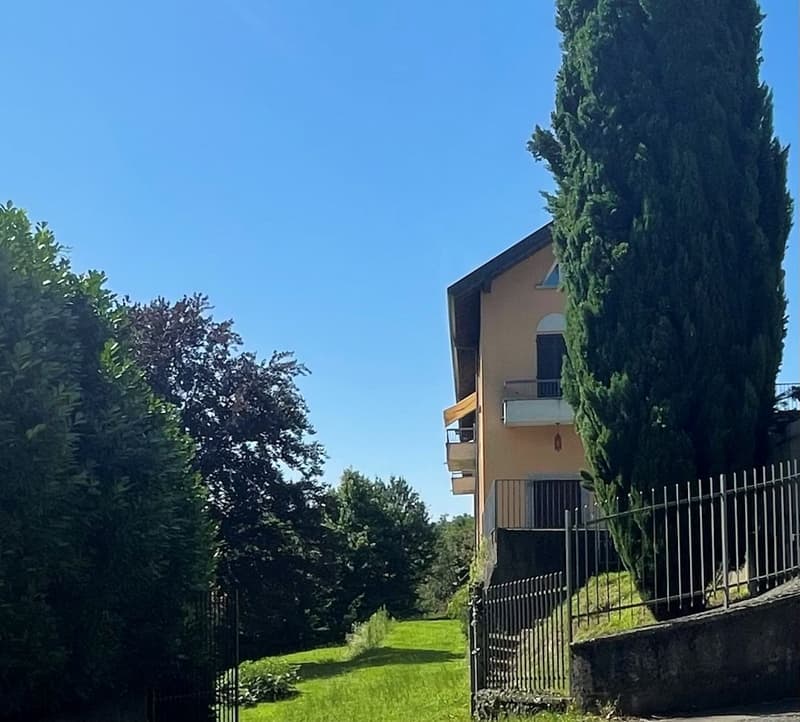 2 story house, beige walls, balcony, metal fence, green lawn, trees