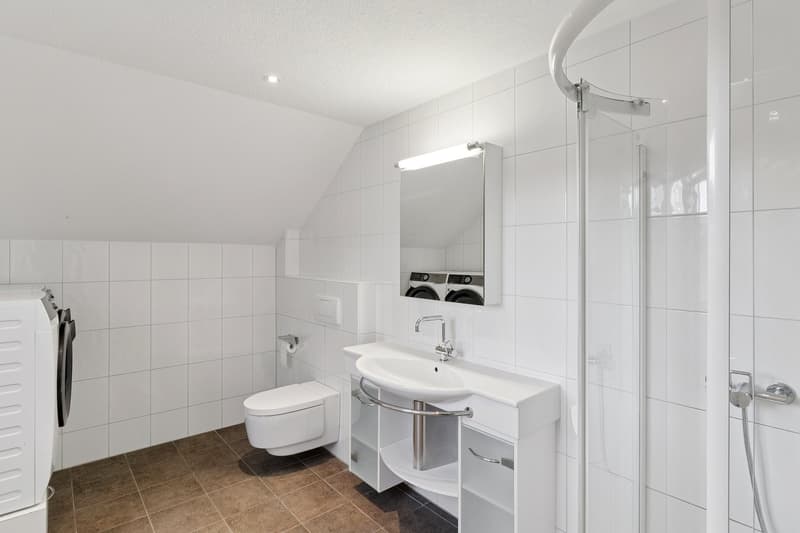 Helles Badezimmer der OG-Wohnung mit Dusche, eigener Waschmaschine sowie eigenem Tumbler
