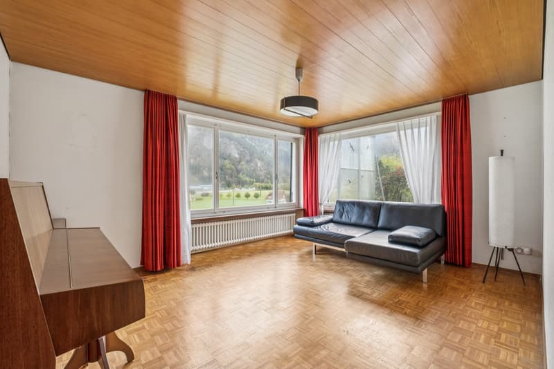 Der Wohnbereich mit grossen Panoramafenstern bietet viel Licht und überzeugt mit klassischem Klötzliparkett