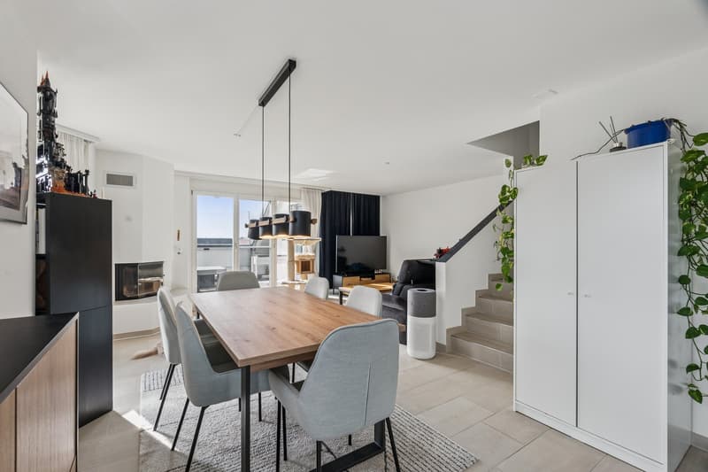 Wohnzimmer mit Kamin und grossen Fensterfronten für ein helles Ambiente
