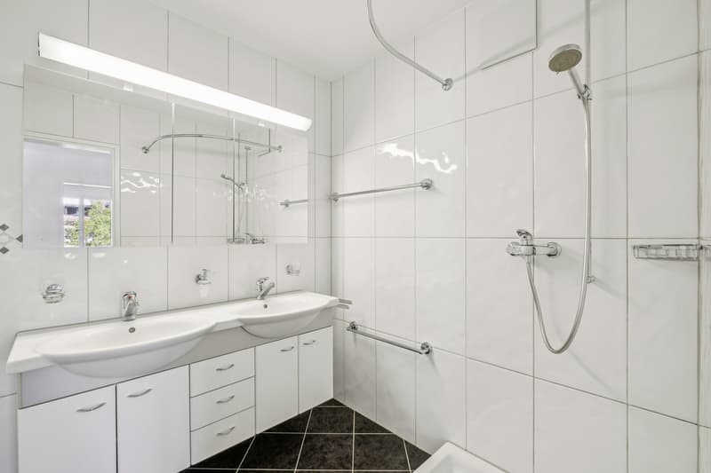Mit Dusche und Doppellavabo ausgestattet, bietet das Badezimmer auf der unteren Etage genügend Platz für die morgendliche Routine, ein separate Toilette ist nebenan