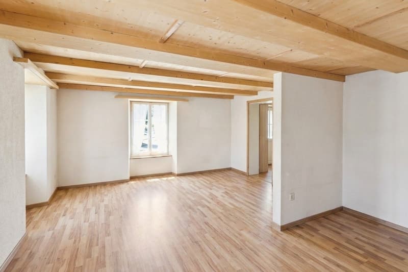 Wohnzimmer mit rustikalen Naturholzdecken und viel Tageslicht